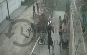 Um dos criminosos aponta uma arma para o casal, que estava em frente à uma residência