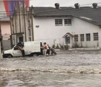 Motoristas empurram veículo em via alagada na Zona Noroeste de Santos