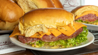 Roxy | Cará Melt: Pão de cará tostado no azeite, salame hamburguês, cheddar, alface, tomate temperado com mel, mostarda e orégano