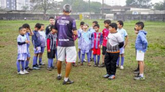 Treinador Luiz Fernando orienta os alunos durante o treino no campo de futebol, em Itanhaém