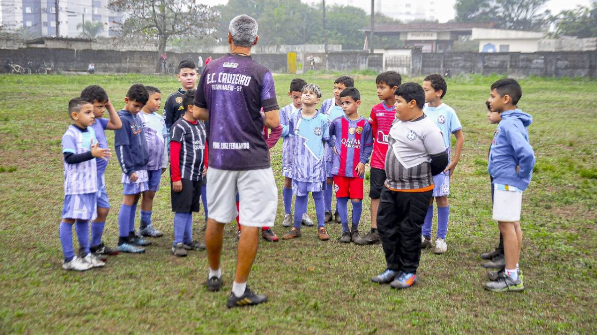 Treinador Luiz Fernando orienta os alunos durante o treino no campo de futebol, em Itanhaém