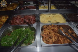 O cardápio inclui uma variedade de acompanhamentos, como arroz, couve, farofa e laranja, tudo para complementar essa deliciosa refeição