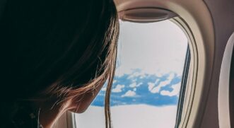 Passageira olhando pela janela de avião durante o dia