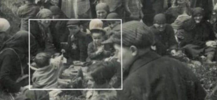 Menino oferece flor a outra criança durante o holocausto