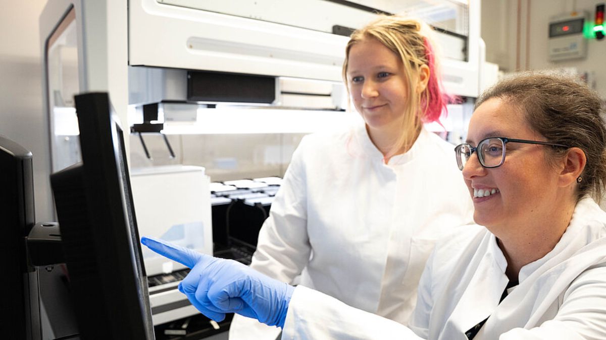 A cientista Ana Rita Brochado e Laura Sniegula analisam dados do robô de pipetagem; estudo mostra que a cafeína altera proteínas de transporte na E. coli/ Leon Kokkoliadis/CMFI/Universidade de Tübingen