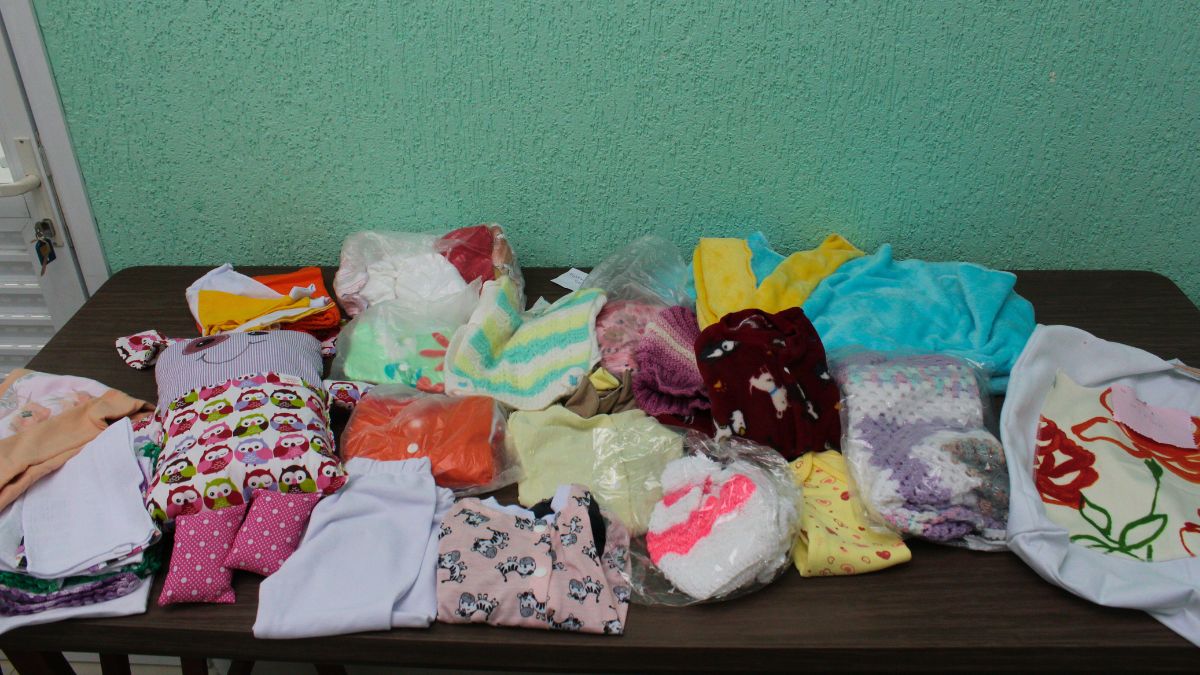 O enxoval conta com 3 pagãos, 2 macacões, 2 casacos, 2 toucas de lã, 2 sapatinhos de lã, 2 fraldas de tecido, 2 panos de boca, manta, cobertor, bolsa artesanal e 'naninha do bem' / Júlia Morgado/Diário do Litoral
