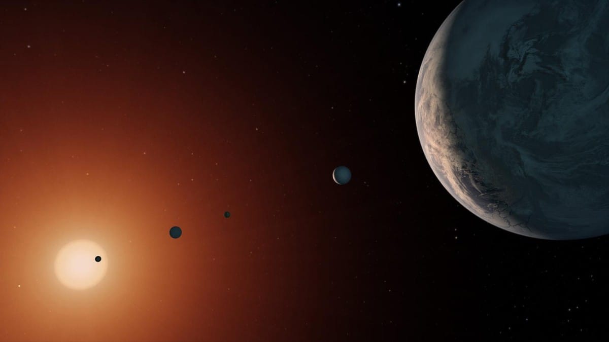Ilustração mostra o sistema TRAPPIST-1 a partir de um ponto próximo ao planeta TRAPPIST-1f. Alguns planetas provavelmente estão presos por acoplamento de maré, mantendo sempre a mesma face voltada para a estrela / NASA/JPL-Caltech
