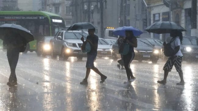 Pessoas atravessando a avenida durante uma manhã de chuva e frio no Brasil