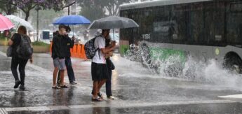 Pessoas na rua diante de uma chuva forte com ventos moderados