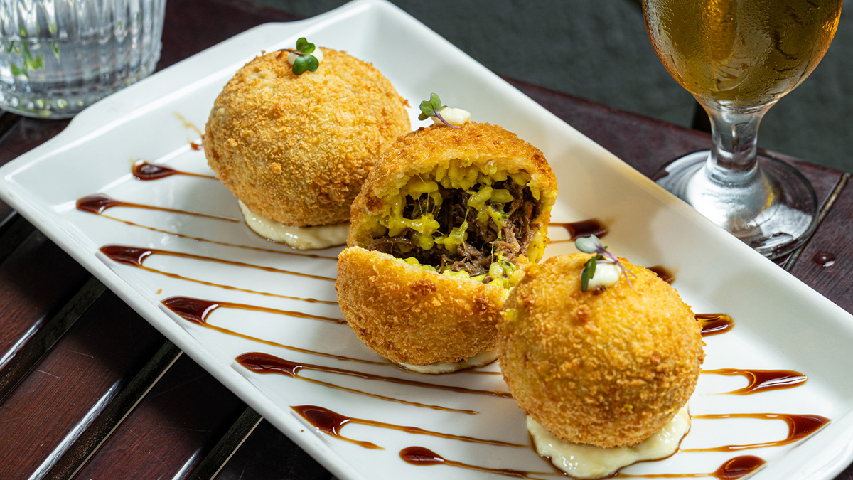 Suppli de ossobuco: Trio de bolinhos crocantes de risoto de açafrão, recheado com ossobuco e acompanhado de maionese artesanal R$ 59 - Divulgação/Ricardo Tuka
