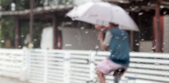 Morador anda de bicicleta e guarda-chuva no litoral de SP