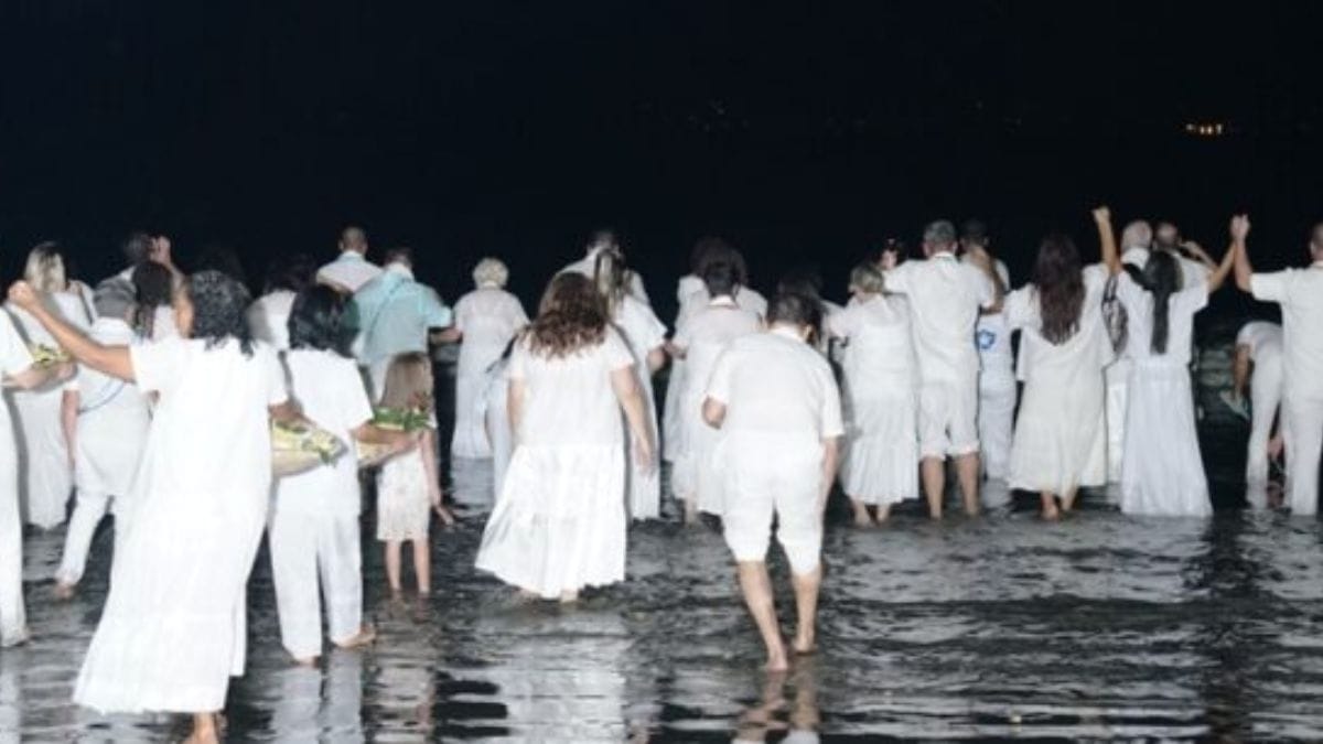 Devotos vestidos de branco avançam em direção ao mar para entregar flores e agradecer à orixá, gesto tradicional da festividade/ Prefeitura Municipal de Caraguatatuba