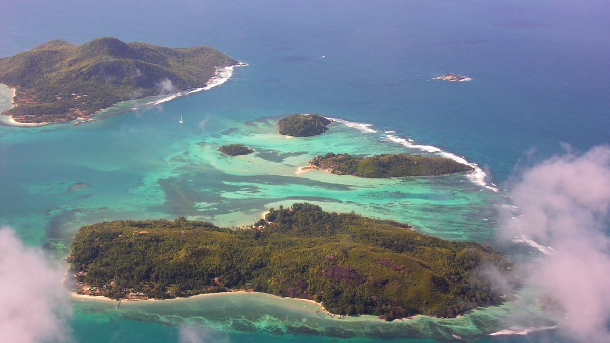 Vista da porção sudoeste de Moyenne Island, em Seychelles, destaca a vegetação preservada, o mar de tons azul-turquesa e o perfil natural que transformou a ilha em referência de conservação ambiental / Jean-Francis Martin/Wikimedia Commons