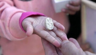 Ao notar uma pedra diferente no chão, a menina a limpou e revelou um objeto oval com inscrições misteriosas