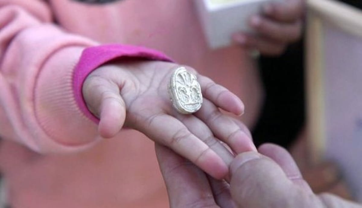 Ao notar uma pedra diferente no chão, a menina a limpou e revelou um objeto oval com inscrições misteriosas