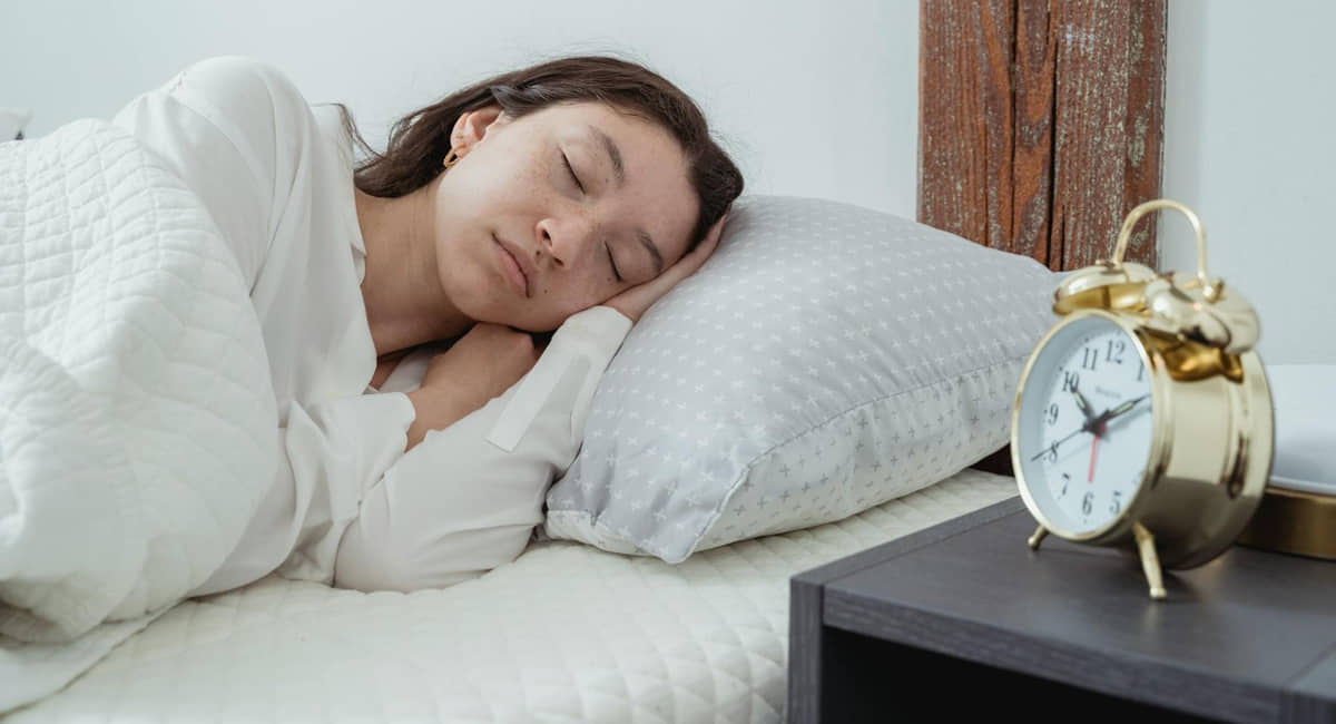 Mulher dorme serenamente com o despertador bem ao seu lado