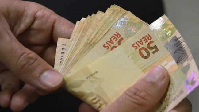 Pessoa contando notas de dinheiro em reais