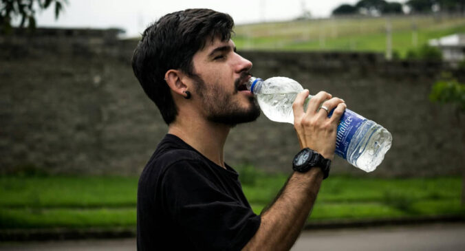 Homem bebe água gelada em dia de calor forte no Brasil