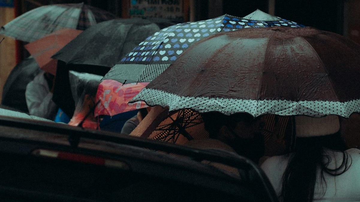 Pessoas de protegem de pancada de chuva na rua