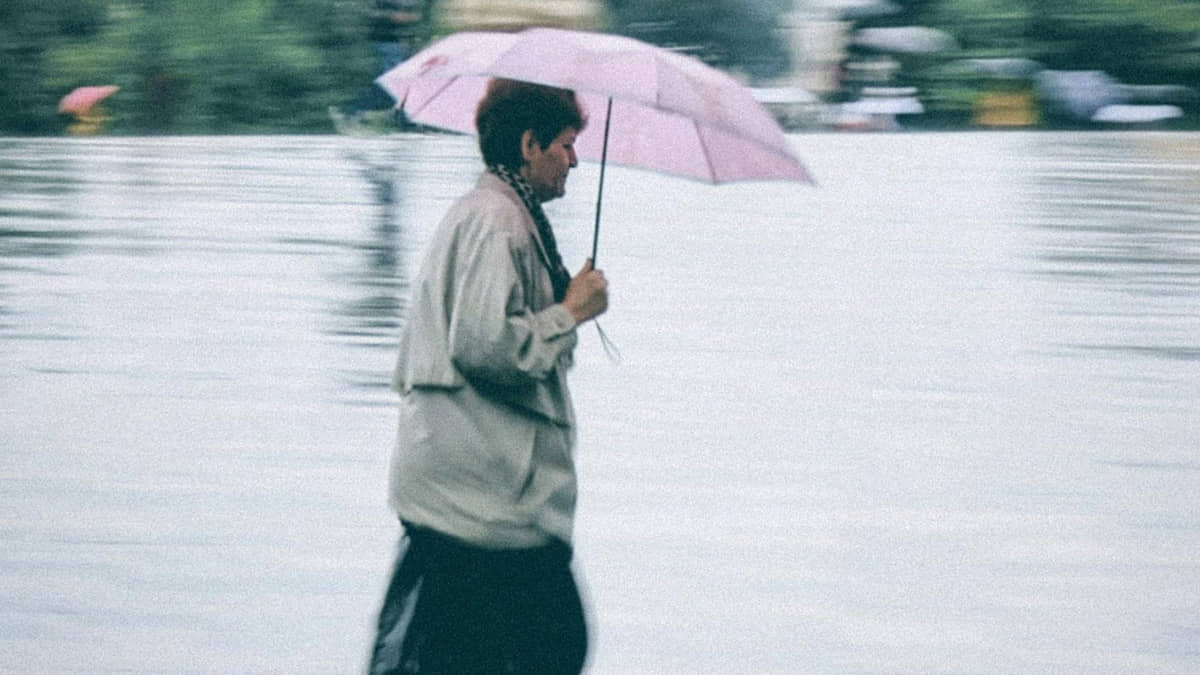 Mulher anda com seu guarda-chuva após virada no tempo causada por frente fria